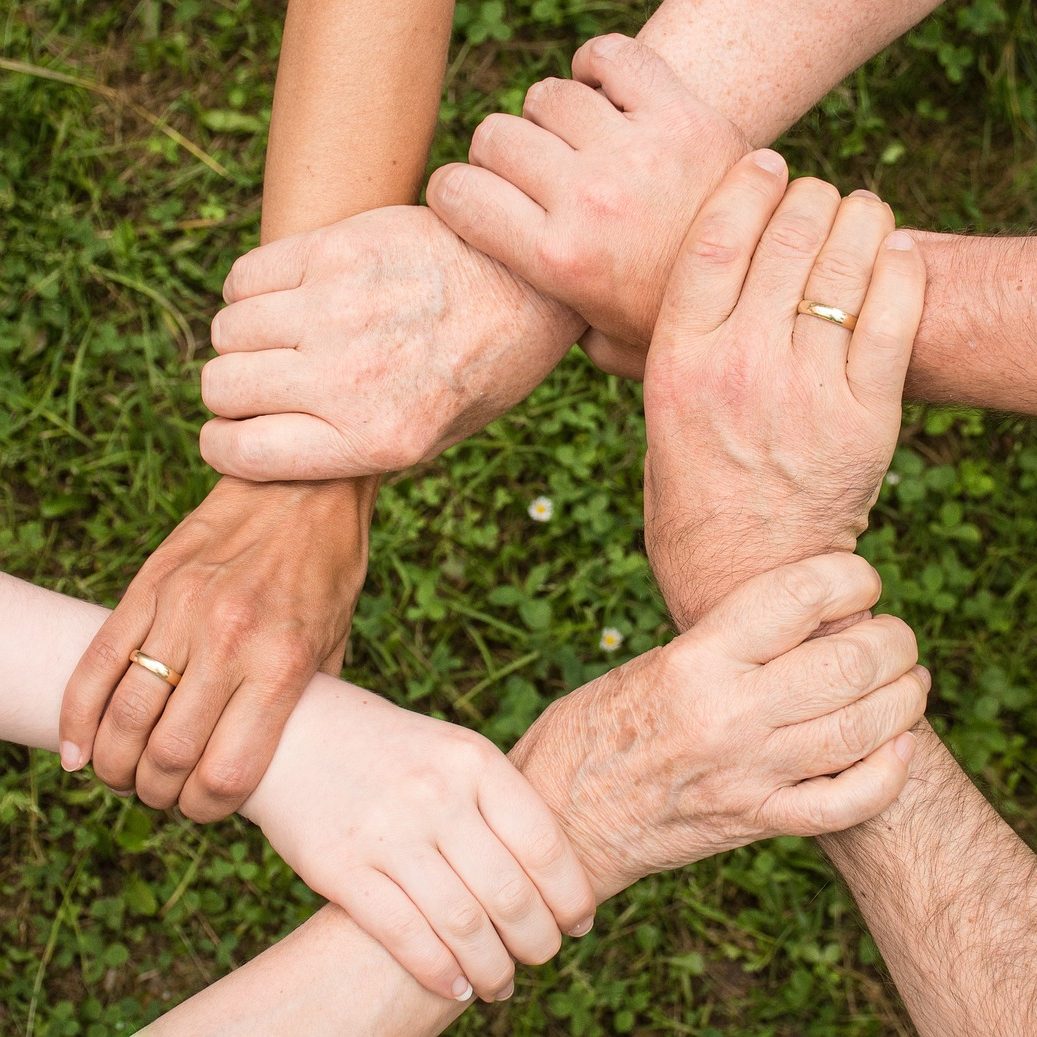 six people holding hands in a circle